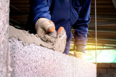 Profesyonel bir işçinin beton tuğlalar ve çimento ile tuğla duvar örmek için çakı kullanması. İş fikirleri ve inşaat endüstrisi