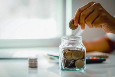 Bozuk para ve hesap makinesi desteleri, para biriktirme konsepti, finansal planlama, gelecek için yatırım ve emeklilik fonuyla birlikte cam kavanoza para koymak..