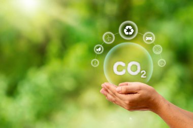 Eldeki CO2 sembolü veya karbondioksit, sürdürülebilir çevre uygulamaları kavramını yansıtan sera gazlarından biri olan karbondioksit emisyonunun azaltılmasını temsil etmektedir..