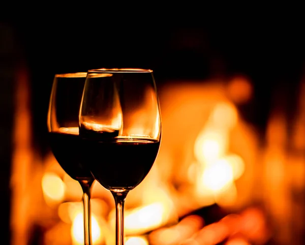 Two glasses of red wine on the background of fireplace lights. Christmas holiday concept