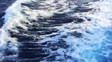 Okyanus dalgaları, izler ve köpük, güneşli bir günde mavi denizde hızla hareket eden motorlu teknenin arkasında. Arka planda adalar ve dağlar var. Yaz tatili ve tatil gezisi konsepti