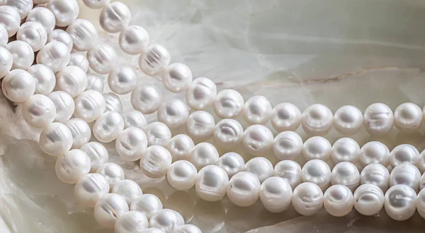 Nature white string of pearls on marble background in soft focus, with highlights