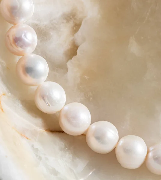 Nature white string of pearls on marble background in soft focus, with highlights