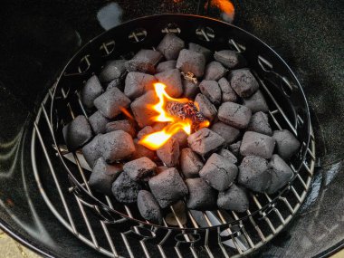 Mangal ızgarasında mangal kömürü arasında yanan bir çakmak..