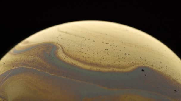 石鹸バブルの表面に金色の美しいパターン 黒の背景でクローズアップ 部分的偏在 — ストック動画