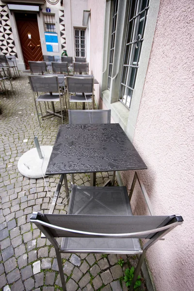 Natte tafels en stoelen in regenachtige dag in stoep cafe — Stockfoto