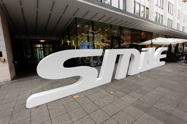 BERLIN, GERMANY - NOVEMBER 12, 2014: Dental care shop Swiss Smile with 3D logo on pavement at shopping street Kurfuerstendamm in Berlin, Germany on November 12, 2014 — Stock Photo, Image