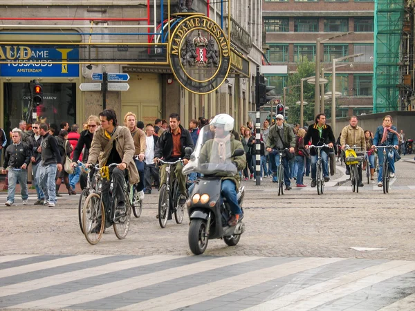 AMSTERDAM, PAÍSES BAJOS - 19 DE OCTUBRE DE 2006: La gente que monta bicicletas en la calle central en la parte histórica de la ciudad el 19 de octubre de 2006 en Amsterdam, Países Bajos — Foto de Stock