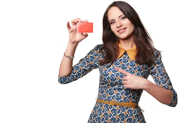Beautiful woman in colorfull dress holding empty credit card and pointing at it,  isolated on white background — Stock Photo, Image