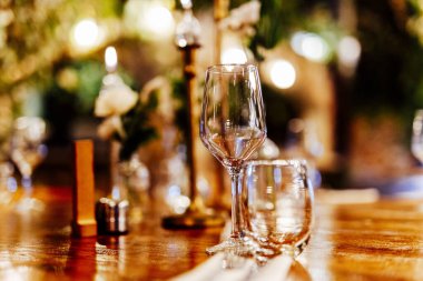 Sıcak bir restoran atmosferinde şarap kadehleri ve sıcak altın bokeh ışıkları olan zarif bir Noel sofrası..