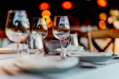 Sıcak bir restoran atmosferinde şarap kadehleri ve sıcak altın bokeh ışıkları olan zarif bir Noel sofrası..