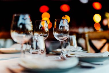 Sıcak bir restoran atmosferinde şarap kadehleri ve sıcak altın bokeh ışıkları olan zarif bir Noel sofrası..