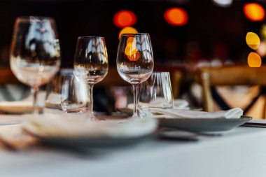 Sıcak bir restoran atmosferinde şarap kadehleri ve sıcak altın bokeh ışıkları olan zarif bir Noel sofrası..