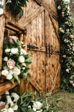 Kahverengi ahşap dekoratif kapılar güzel taze çiçeklerle süslenir, büyük bir olay için düğün dekorasyonu, açık hava dekorasyonu, açık hava düğün kemeri.