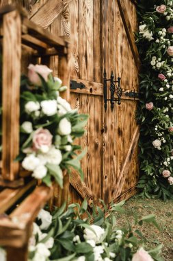 Kahverengi ahşap dekoratif kapılar güzel taze çiçeklerle süslenir, büyük bir olay için düğün dekorasyonu, açık hava dekorasyonu, açık hava düğün kemeri.