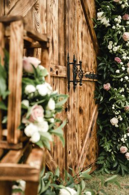 Kahverengi ahşap dekoratif kapılar güzel taze çiçeklerle süslenir, büyük bir olay için düğün dekorasyonu, açık hava dekorasyonu, açık hava düğün kemeri.