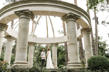 Gelin ve damat düğün günlerinde, bahar doğasında dışarıda yürüyorlar. Yeni evli, mutlu yeni evli bir kadın ve yeşil bir parkta kucaklaşan bir adam. Dışarıda sevgi dolu bir çift..