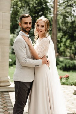 Gelin ve damat düğün günlerinde, bahar doğasında dışarıda yürüyorlar. Yeni evli, mutlu yeni evli bir kadın ve yeşil bir parkta kucaklaşan bir adam. Dışarıda sevgi dolu bir çift..