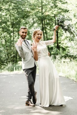 Yeşil bir parkta kucaklaşan ve gülümseyen yeni evliler. Dantel bir elbise içinde gelin ve damadın portresi. Yeni evli çiftin düğün günü.