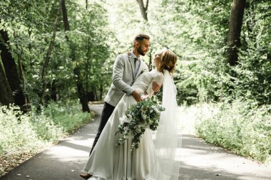 Açık havada dans eden evli bir çift, boş alan. Gelin ve damat kucaklaşması, bulanık yeşil çimen arka planı. Düğün dansının ilk konsepti