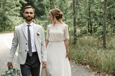 Gelin ve damat düğün günlerinde, bahar doğasında dışarıda yürüyorlar. Yeni evli, mutlu yeni evli bir kadın ve yeşil bir parkta kucaklaşan bir adam. Açık havada sevgili bir çift. Gelin ve damat