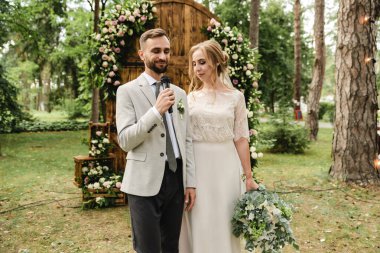 Yeni evliler mikrofonla şarkı söylerler. Yeni evli çiftimiz düğün vaatlerini güzel bir düğün kemerinin, düğün töreninin ve düğün töreninin arka planında verirler.