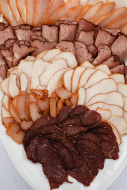 Etli meze, düğün masasında büyük bir tepsi doğranmış et, et kesme tahtası, büfe masası, çeşitli organik etler.