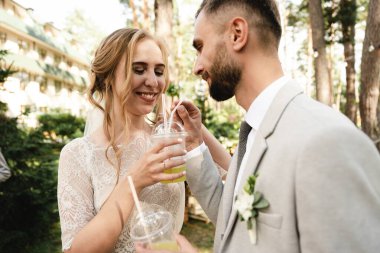 Gelin ve damat, doğadaki misafirler çemberinde içkilerinin tadını çıkarırlar. Gelin ve damat, bahçede misafirlerle birlikte bir içkinin tadını çıkarırlar. Aşık bir çiftin düğün günü.