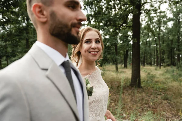 happy and joyful bride and groom walk on the wedding day in the park and look at each other,in the foreground the groom in the background a happy wife,newlyweds go to the ceremony