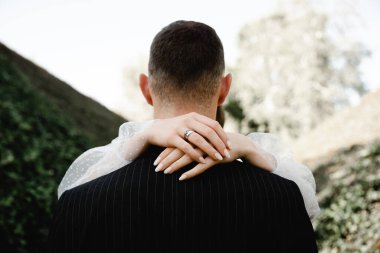 Zengin damat ve gelin, sarmaşıkla kaplı parkta güzel güzel yürüyorlar. Genç bir ailenin düğün günü. Yeni evliler. Evliliğin başlangıcı. Güçlü bir aile. romantik ilişki