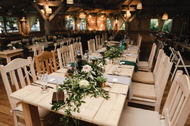 Düğün ziyafeti. Misafirler için şenlik masası. Kırsal tarzda güzel dekore edilmiş ziyafet salonu. Düğün dekoru. Tahta bir masada çiçekler. Avrupa düğünü