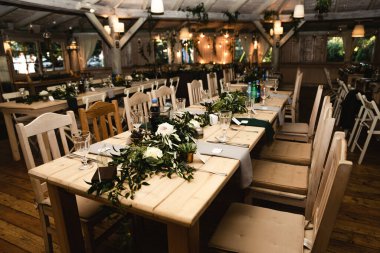 Düğün ziyafeti. Misafirler için şenlik masası. Kırsal tarzda güzel dekore edilmiş ziyafet salonu. Düğün dekoru. Tahta bir masada çiçekler. Avrupa düğünü