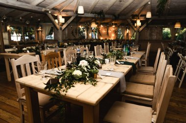 Düğün ziyafeti. Misafirler için şenlik masası. Kırsal tarzda güzel dekore edilmiş ziyafet salonu. Düğün dekoru. Tahta bir masada çiçekler. Avrupa düğünü