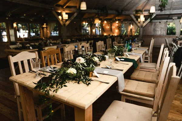 Düğün ziyafeti. Misafirler için şenlik masası. Kırsal tarzda güzel dekore edilmiş ziyafet salonu. Düğün dekoru. Tahta bir masada çiçekler. Avrupa düğünü