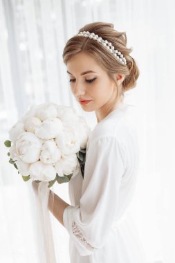 Beyaz cüppeli güzel gelin evine gidiyor. Gelinin ücreti. Yeni evlilerin düğün günü. Gelinin kafasında bir halka. Kızın kafasındaki süsleme. Çiçek buketi.