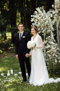 Güzel bir düğün töreni. Damadın arka planında nesty ile düğün kemeri var. Mutlu yeni evliler seremonide. Ziyaret töreni. Güzel bir çift..