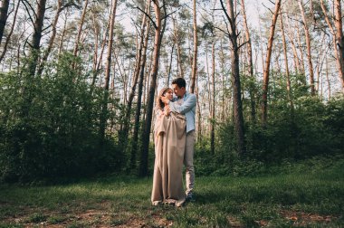 Şık giyimli adam gün batımında gölde kız arkadaşına nazikçe sarılıyor. Kareli kumaşla sarılıyor. Romantik bir buluşma.