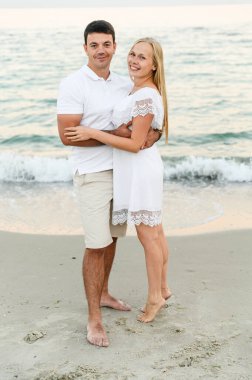 Mutlu çift gün batımında deniz kıyısında sarılıyor. Aşıkların yaz aşkı. Denize doğru yürü. Balayına çıkmış yeni evliler. Romantik zamanlar. Mutlu gençler..