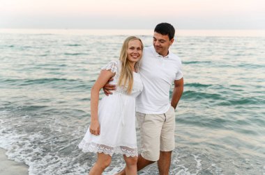 Okyanus kenarındaki aşıklar sarılıp eğleniyorlar. Karı koca gün batımında deniz kenarında kucaklaşır. Tatildeki aşıklar. Yaz tatili. Okyanusta romantik bir yürüyüş.