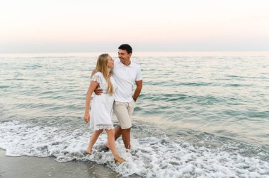 Okyanus kenarındaki aşıklar sarılıp eğleniyorlar. Karı koca gün batımında deniz kenarında kucaklaşır. Tatildeki aşıklar. Yaz tatili. Okyanusta romantik bir yürüyüş.