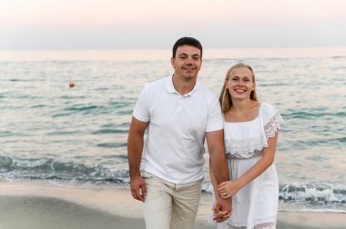 Okyanus kenarındaki aşıklar sarılıp eğleniyorlar. Karı koca gün batımında deniz kenarında kucaklaşır. Tatildeki aşıklar. Yaz tatili. Okyanusta romantik bir yürüyüş.