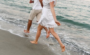 Yazlık elbiseli bir kızla bir adam okyanusun kenarında yürüyor. Karı koca, deniz kenarında romantik bir gün batımında. Aşıklar kumsalda koşar. Yeni evliler için balayı.