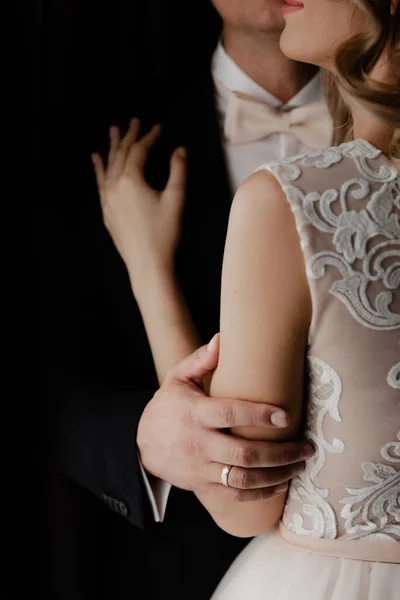 Güzel gelini olan yakışıklı damat karanlık bir odada, aydınlık pencerenin yanında duruyor. Düğün çifti portresi. Düğün günü evlenen çift. Yeni evlilerin toplanması