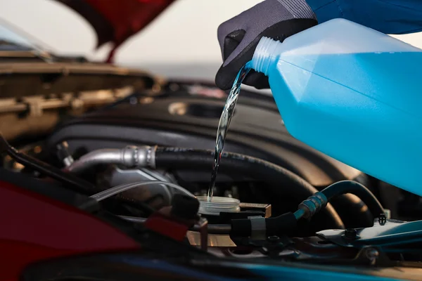 Homem enchendo fluido anticongelante em seu carro — Fotografia de Stock