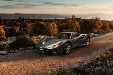 Katowice / Polonya - 06.14.2019: Ferrari F8 Tributo Hırvatistan 'ın Brac adasındaki çakıl yolunda. Arka planda Adriyatik Denizi ve Hvar adası manzarası yer alıyor. Elektronik montaj arabası ve Hırvat manzarası.