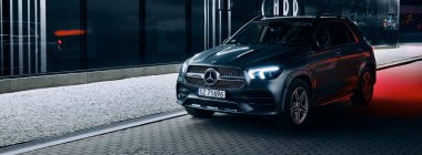 Katowice / Polonya - 01.12.2020: Mercedes GLE modern gece aydınlatmalı bir binanın yanına park etti