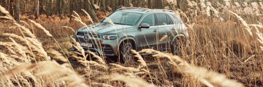 Luxury Mercedes GLE with 4x4 drive on the off-road. V6 engine, 367 hp.The car is on the road partially covered by grasses. There is no driver in the car. Orzesze, Poland - 01.12.2020