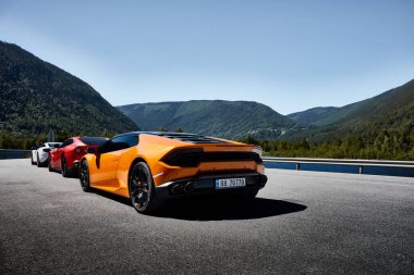 Sarı Lamborghini Huracan, kırmızı Ferrari F12 ve beyaz Mclaren 650 'ler Miland, Norveç' teki gölde park halindeler. 04.06.2016