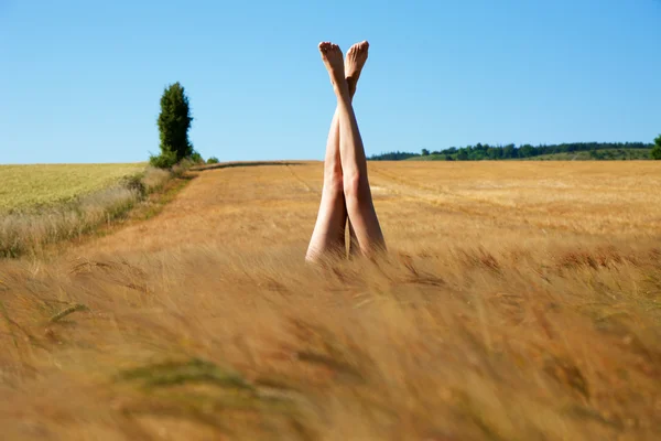 Une jeune femme allongée sur l'herbe les jambes en l'air — Photo