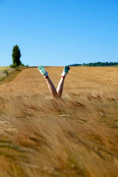 A young woman lying on the grass with her legs in the air — Stock Photo, Image